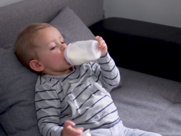 dete pije mleko i leži na krevetu