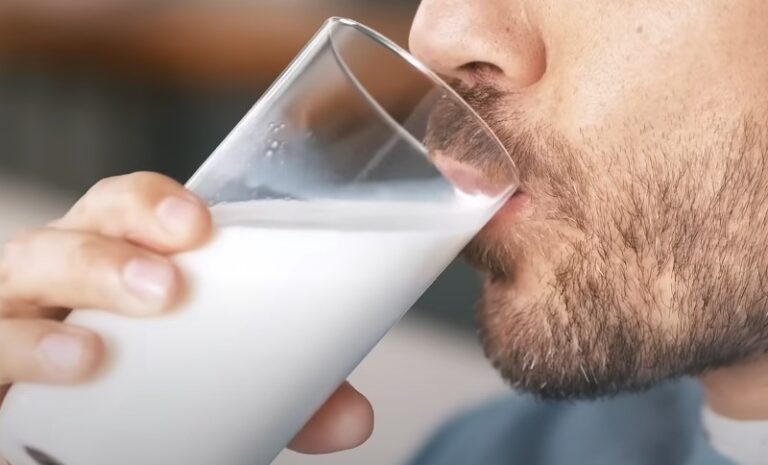 Čovek pije mleko bez laktoze iz staklene čaše